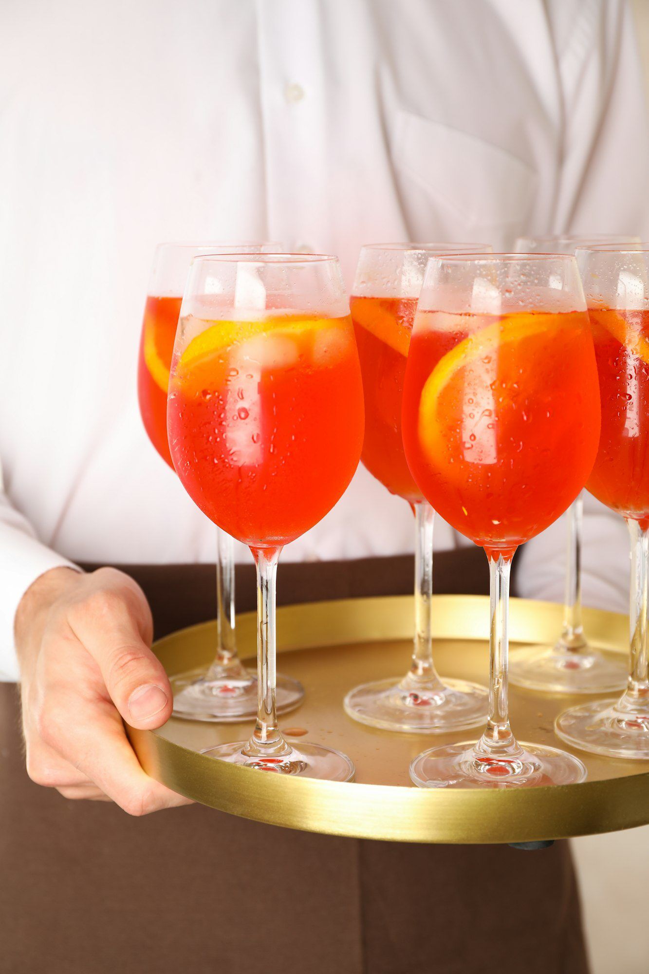 Waiter holding tray with aperol spritz cocktail. Summer drink